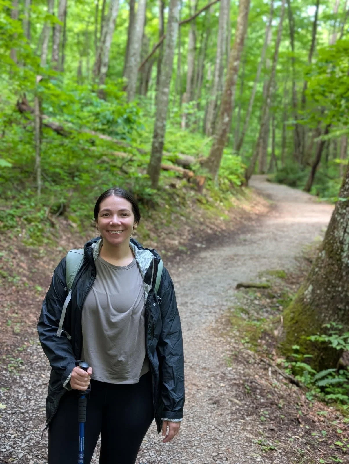 Victoria Bryant, Sprouts facilitator hiking with a hiking pole in the woods.