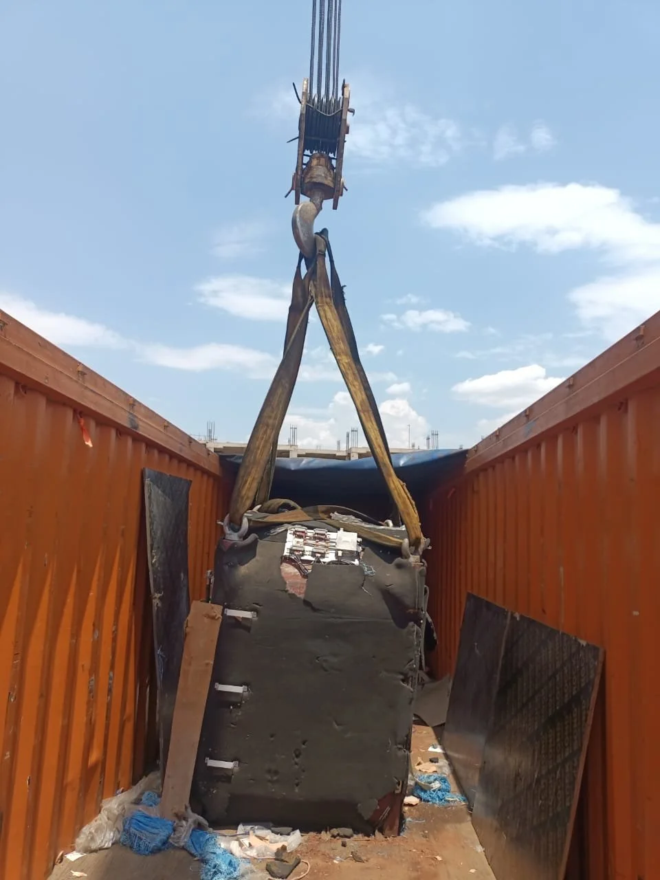 MRI magnet being lifted out of a shipping container by crane