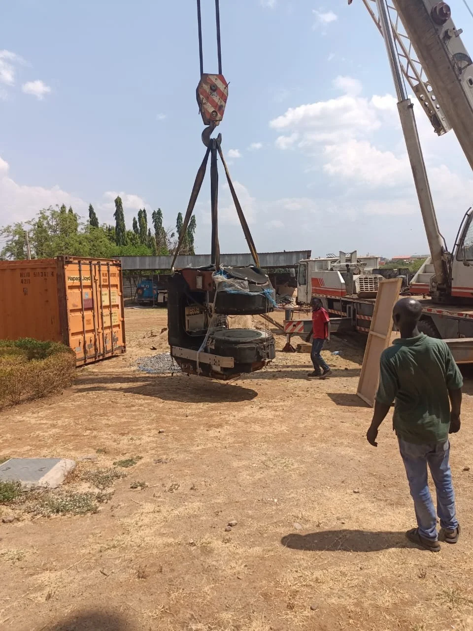 Crane carrying an open MRI magnet across the hospital site under engineer supervision