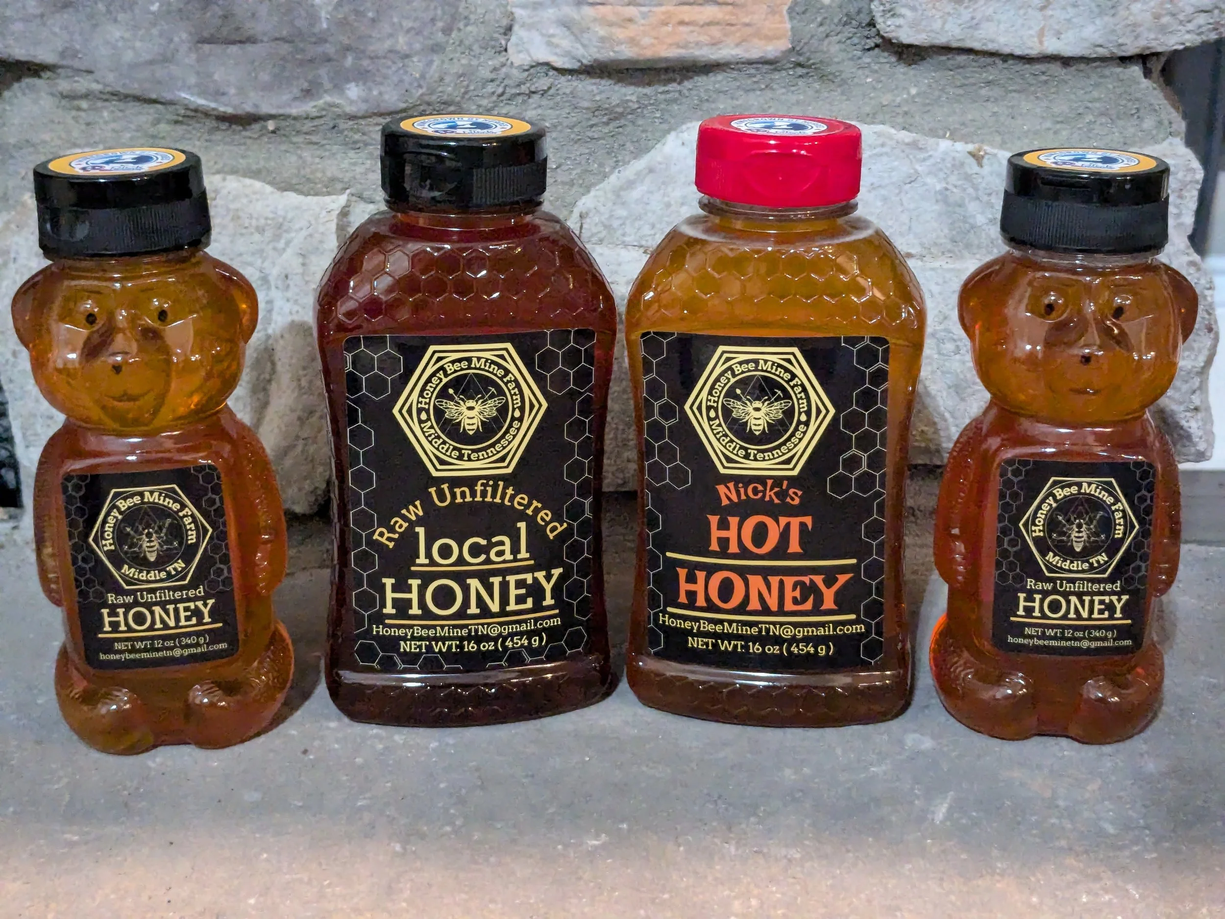 A picture of 3 bottles of  Honey Bee Mine's  Raw unfiltered local Honey and 1 bottle of Nick's Hot Honey