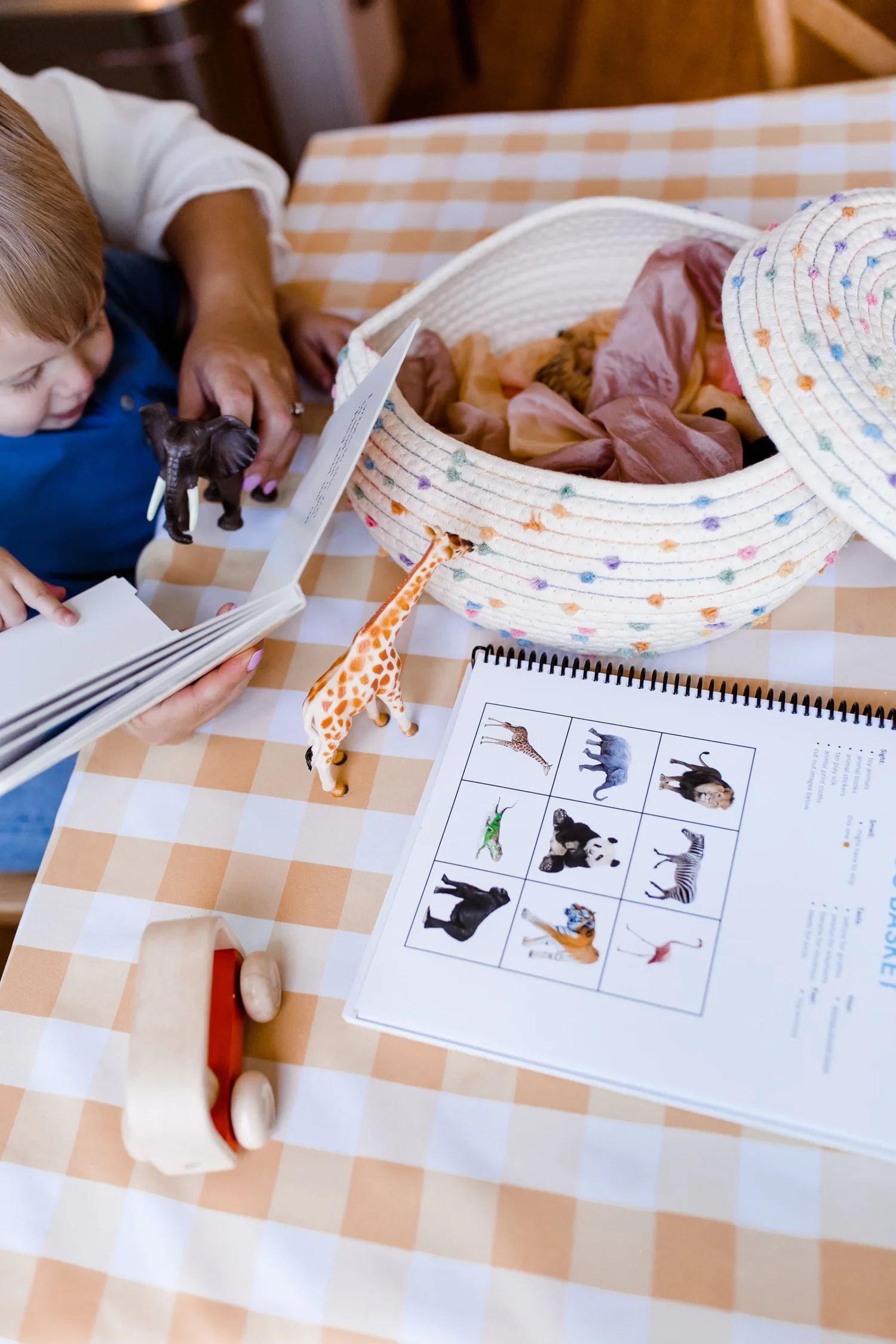Basket of toy animals next to a printable animal matching page for a one-year-old