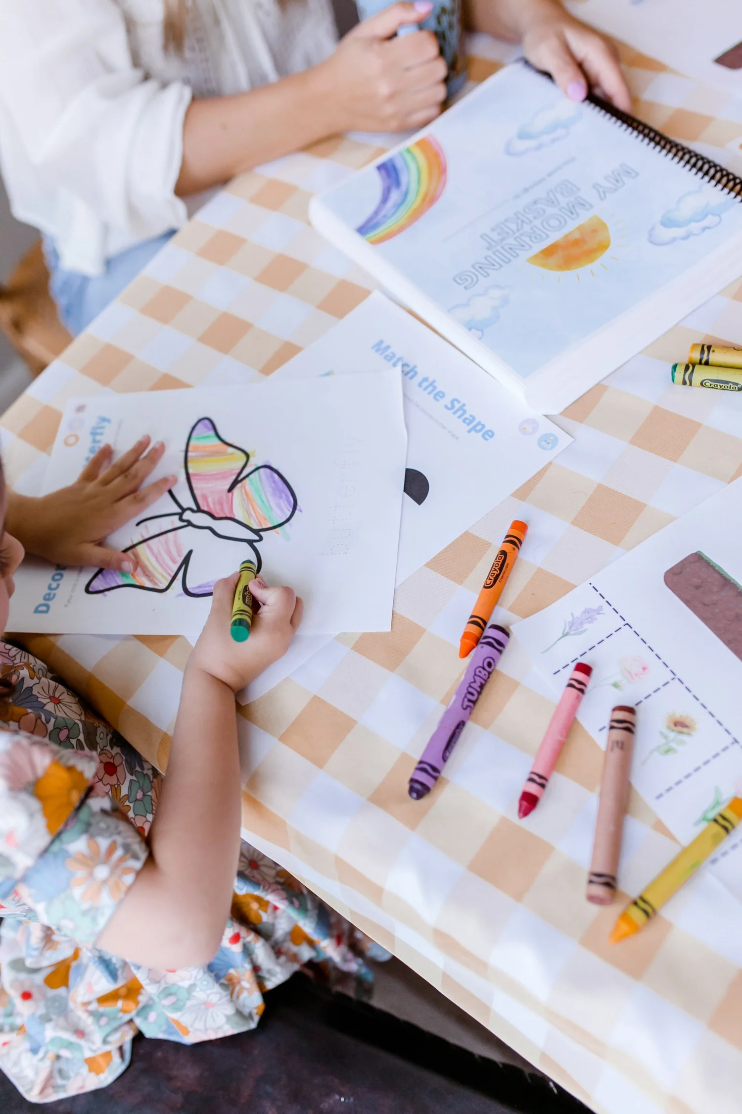 Toddler coloring a butterfly activity page with crayons from a toddler morning basket