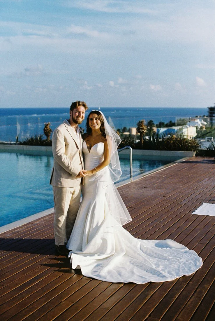 Bride and groom standing together by the pool with ocean view in Cancun, Mexico, captured on film wedding photography