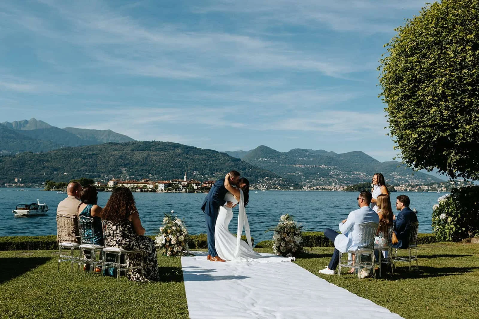 Groom kissing bride during ceremony at Villa Aminta, Lago Maggiore, with the lake, mountains and town of Stresa in the background.