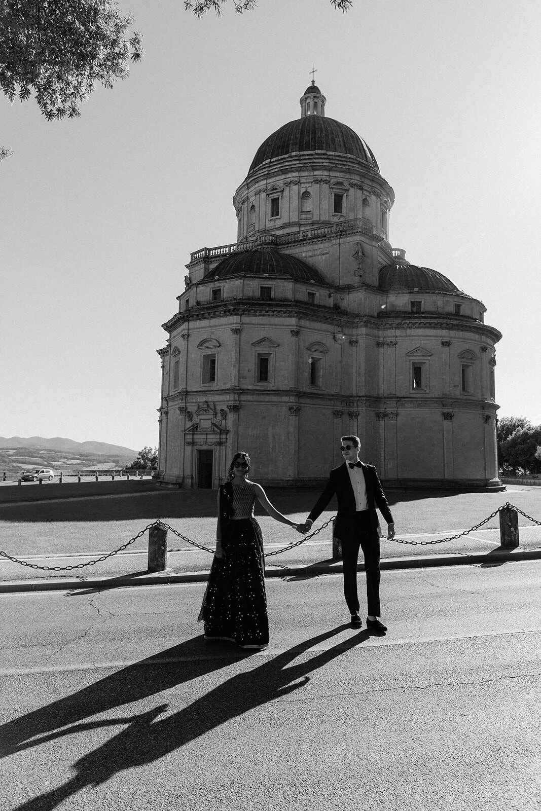Bride and groom holding hands in front of the domed Renaissance church at Todi, Umbria — Italy wedding portrait.