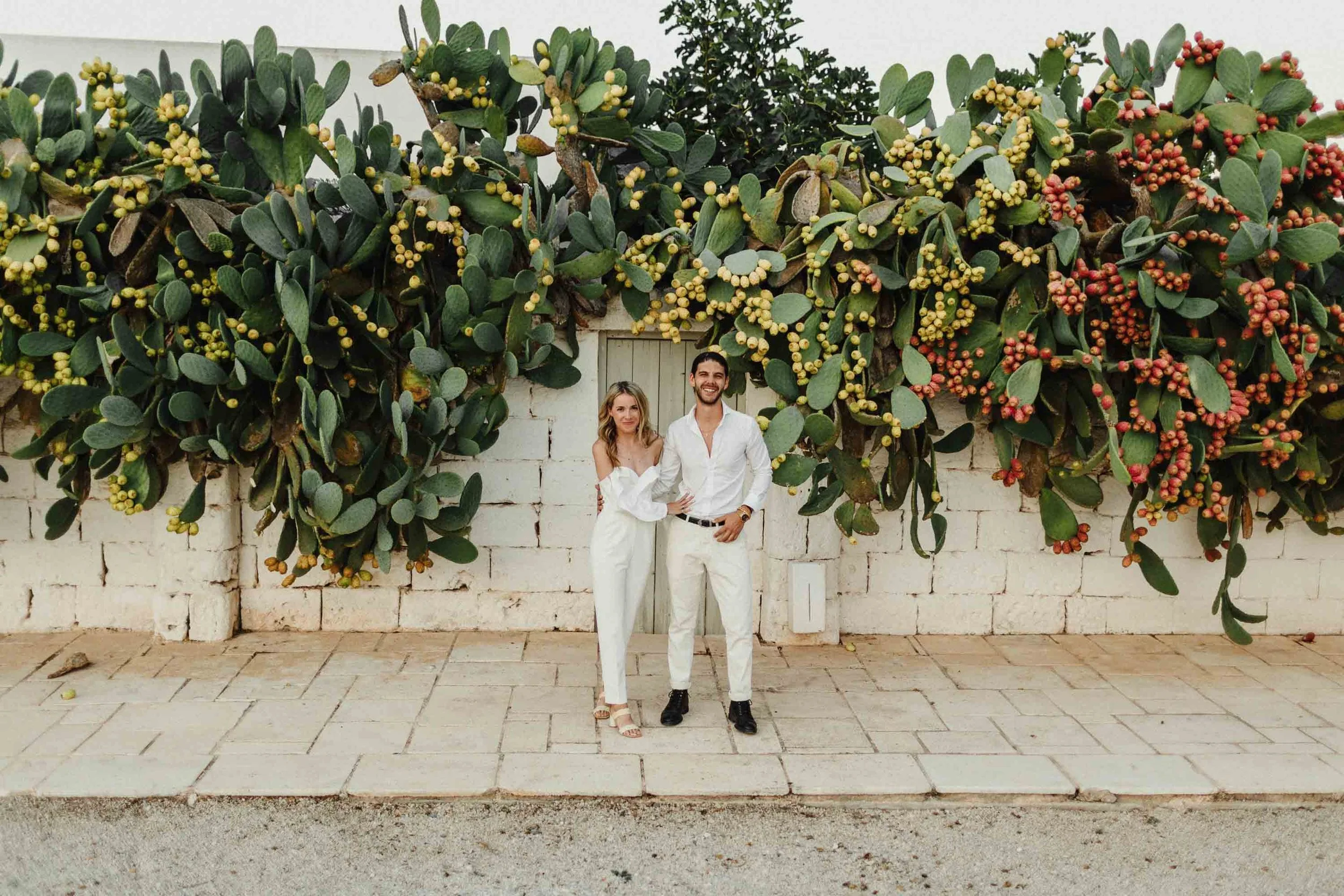bride and groom posing in front of cactus at destination wedding at masseria potenti venue in italy