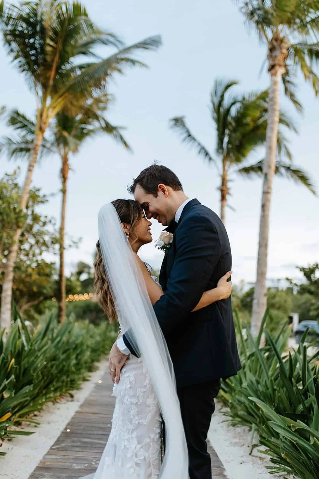Bride and groom foreheads together on a palm-lined path at Finest Playa Mujeres, Cancún