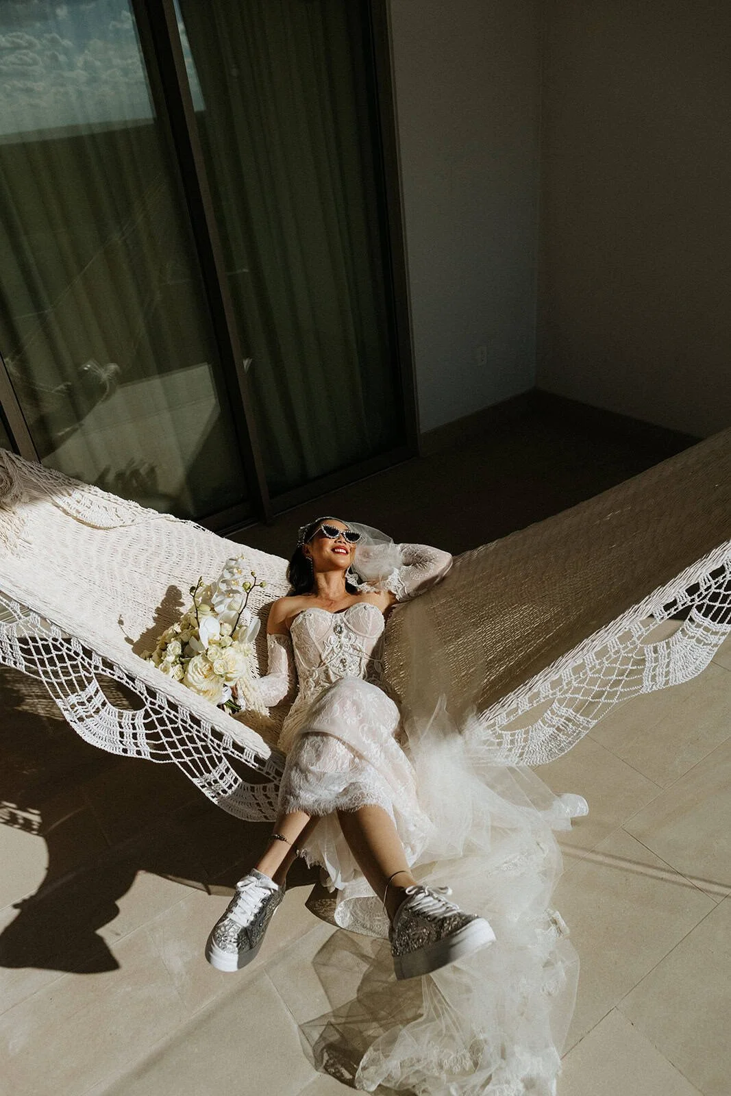 Bride relaxing in a hammock with bouquet and sunglasses at a Riviera Maya destination wedding