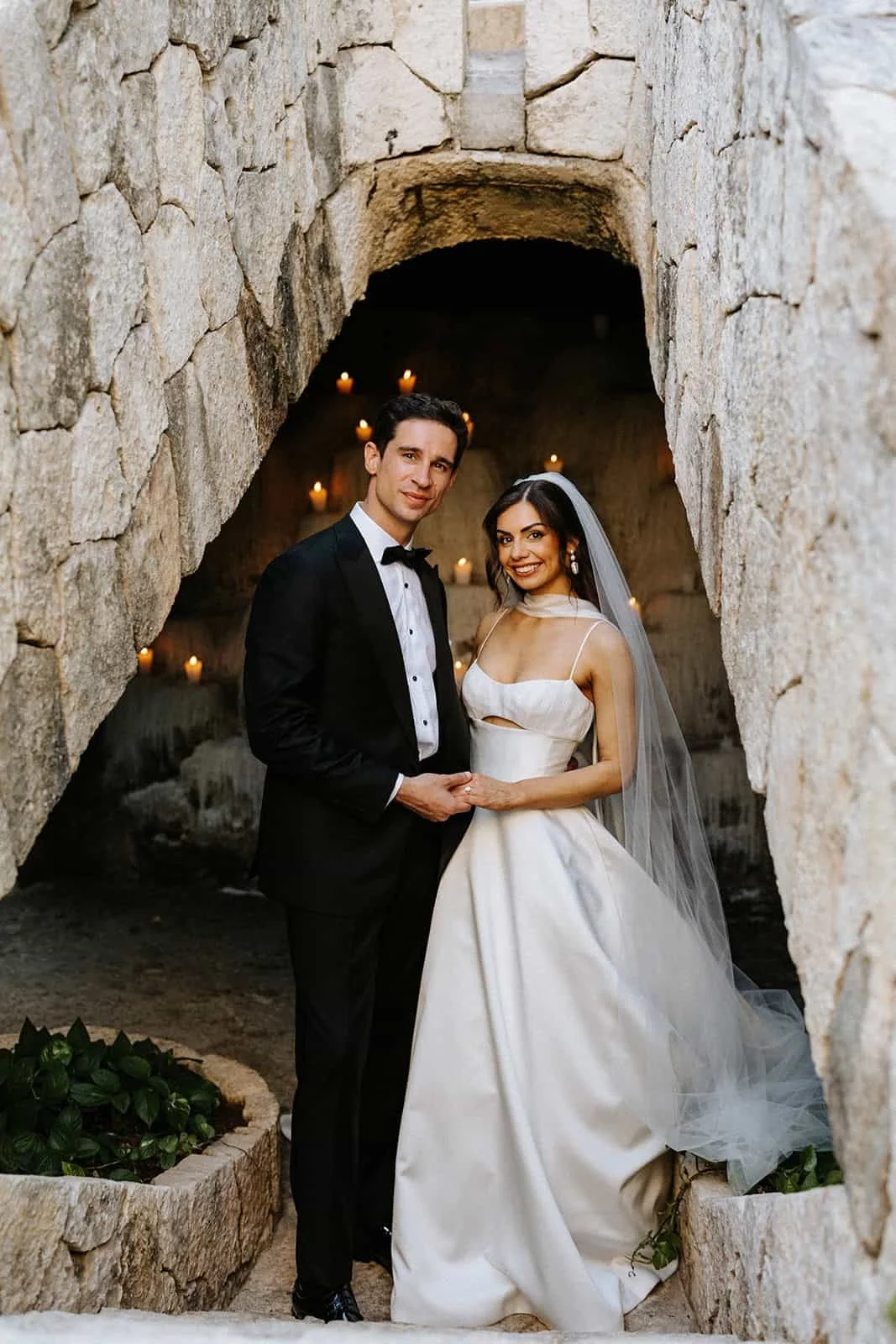 Couple standing together in candlelit stone arch during wedding in Riviera Maya Mexico