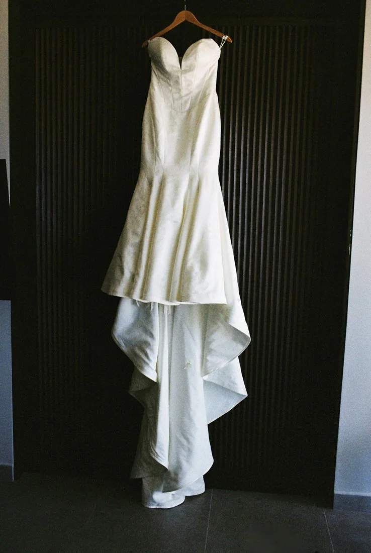 Bride’s elegant white gown hanging on a wooden hanger before the wedding ceremony in Cancun, Mexico.