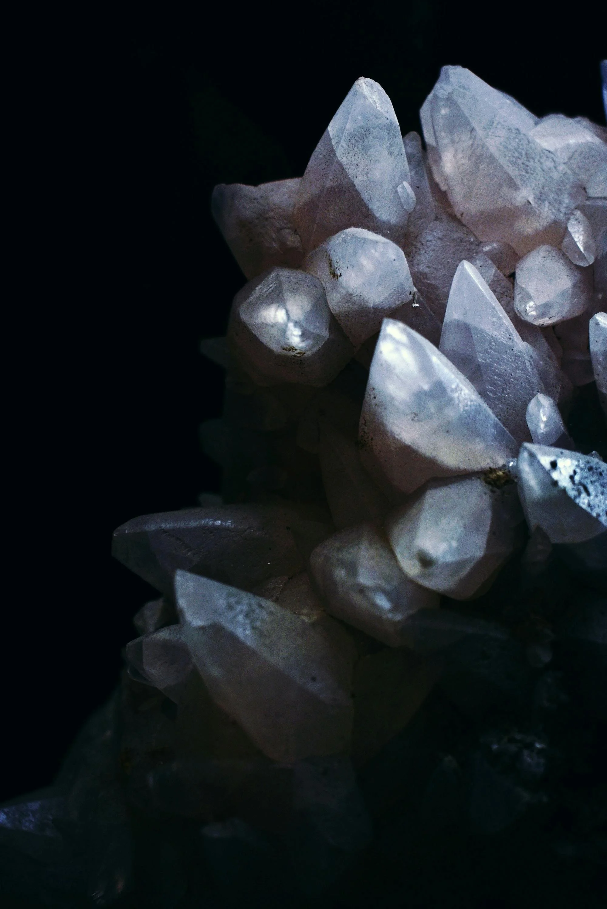 Close-up of a cluster of clear quartz crystals on a dark background.