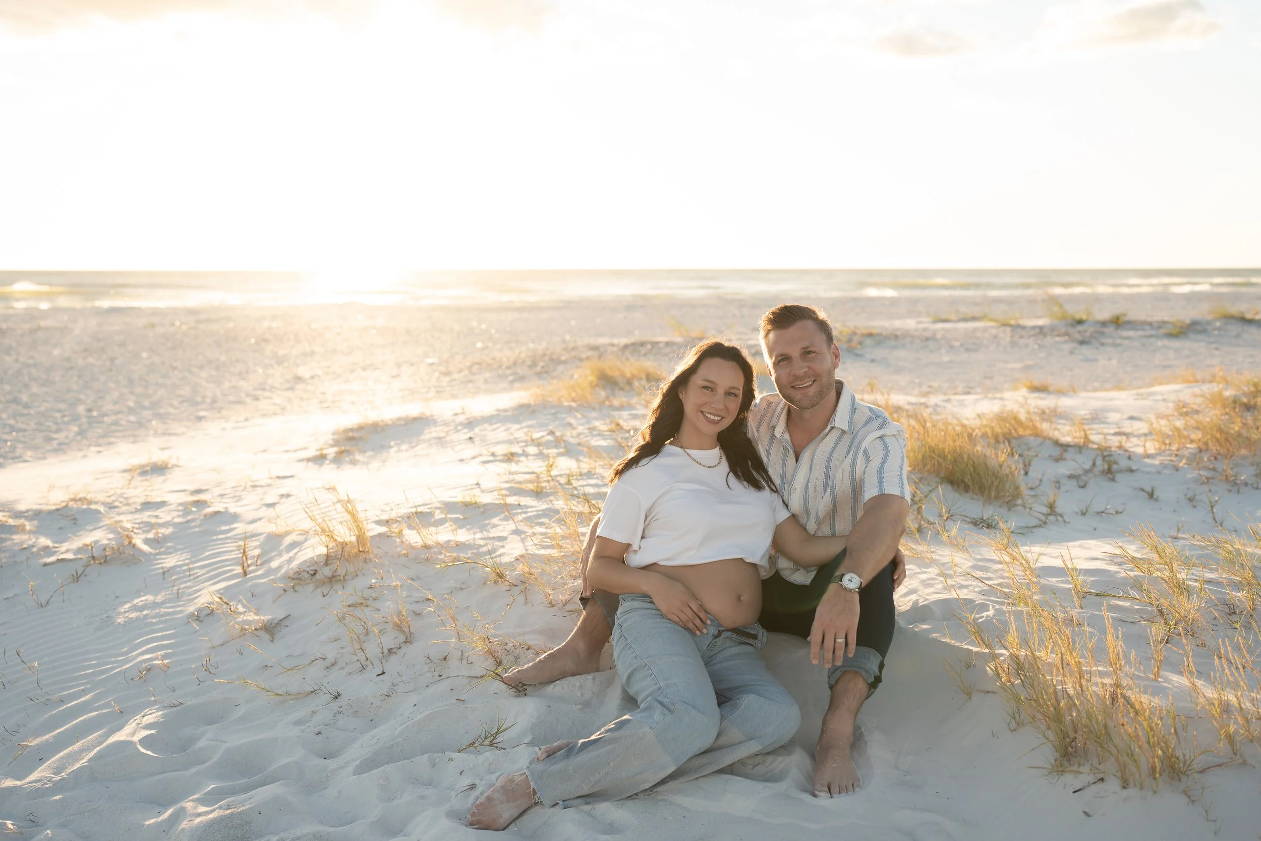 Couple sitting on a bench at the beach, gazing at each other affectionately.