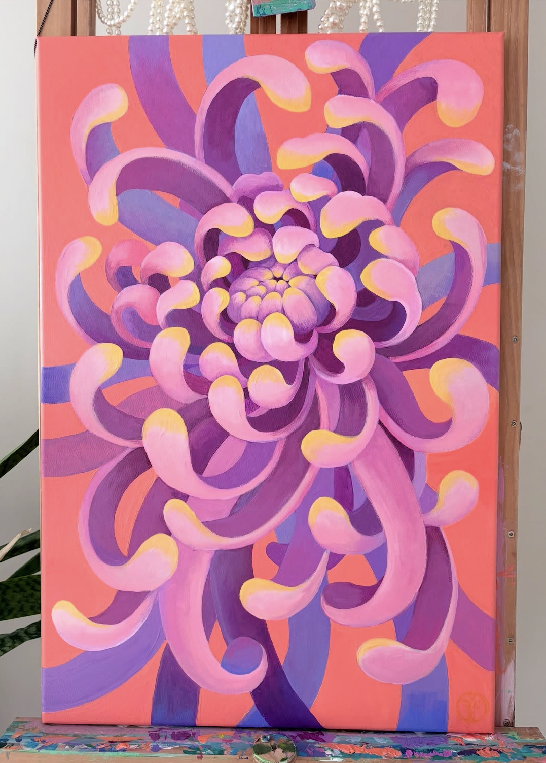Abstract painting of a large, multi-layered flower in shades of pink, purple, and yellow on a pink background.