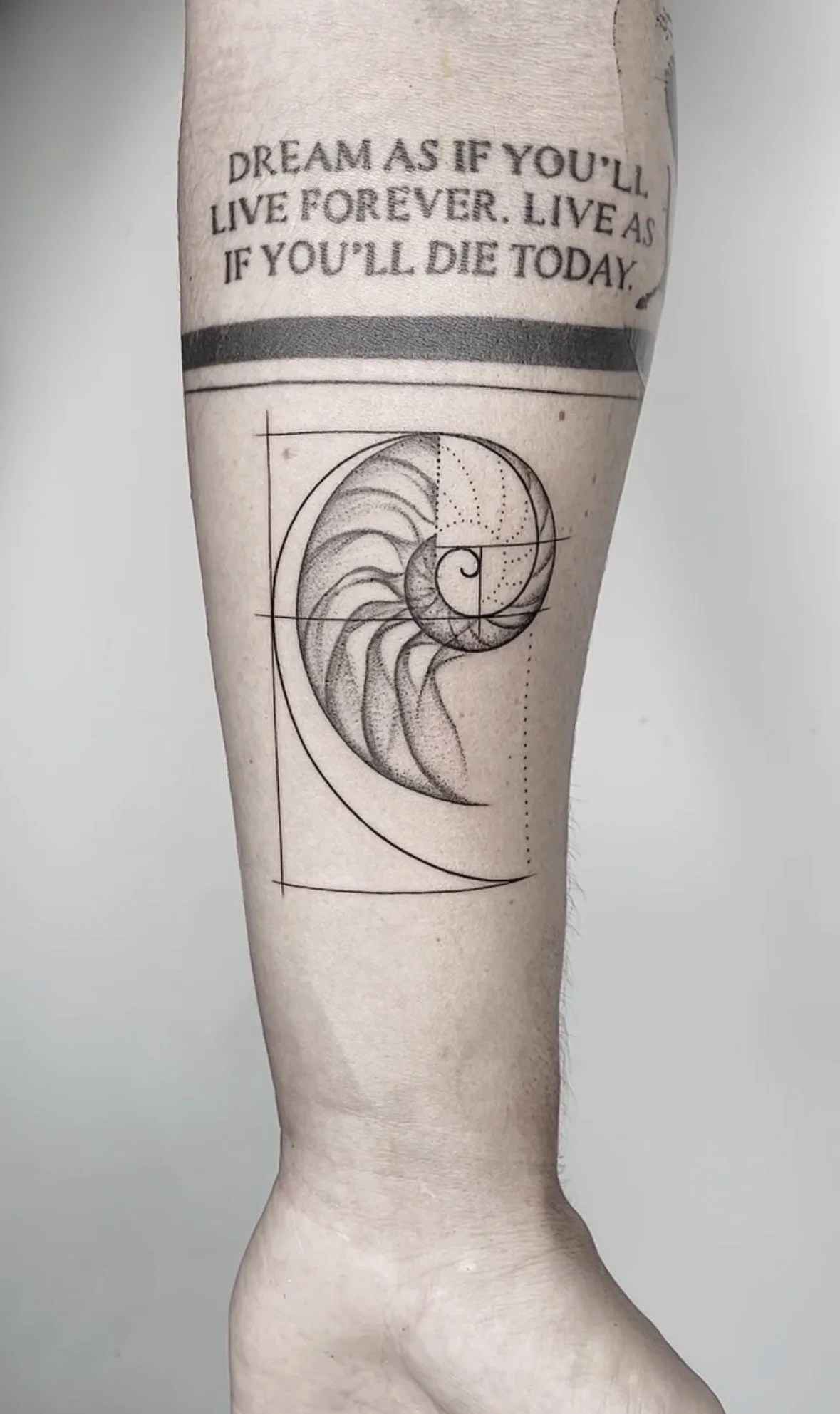 Tattoo of a spiral shell and geometric lines on a person's leg below the knee, with motivational quote above.