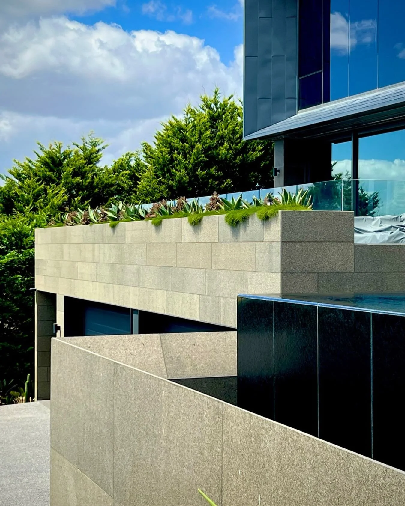 Concrete. Sky. Green.

This is what happens when architecture holds its nerve&hellip; and the garden whispers instead of shouts.

Layered stone. Strong geometry. Glass floating above texture.
Then just enough life spilling over the edge to soften it 