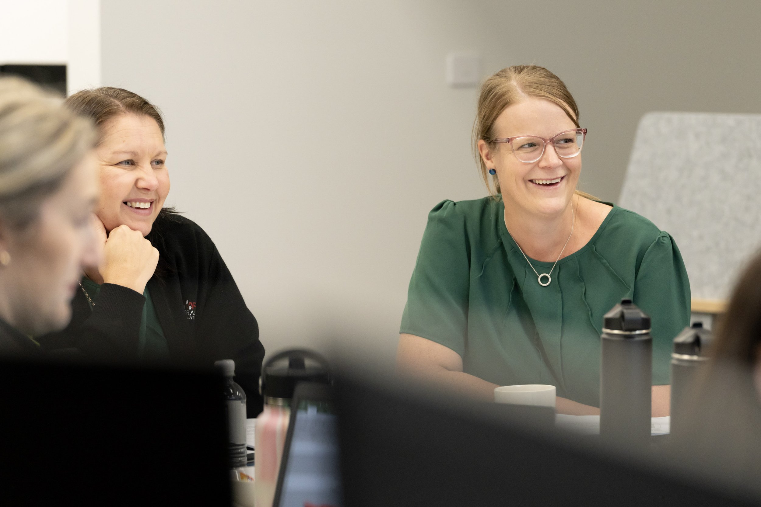 A group of women in a meeting room, laughing and smiling.