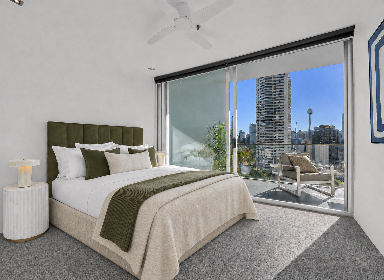 Modern bedroom with a large bed, green and white bedding, and a city skyline view through sliding glass doors that open to a small balcony with a chair and plants.