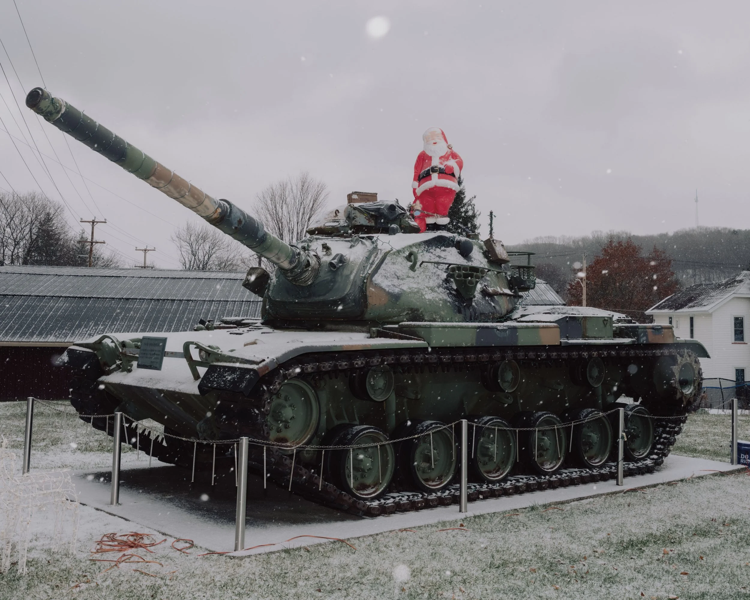 A tank with a Santa Claus figure standing on top of it, in a snowy outdoor setting.