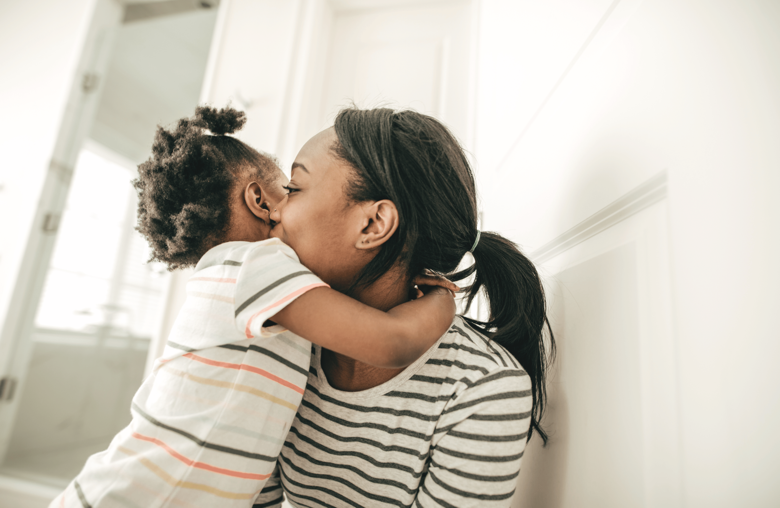 Parent and young child hugging at home