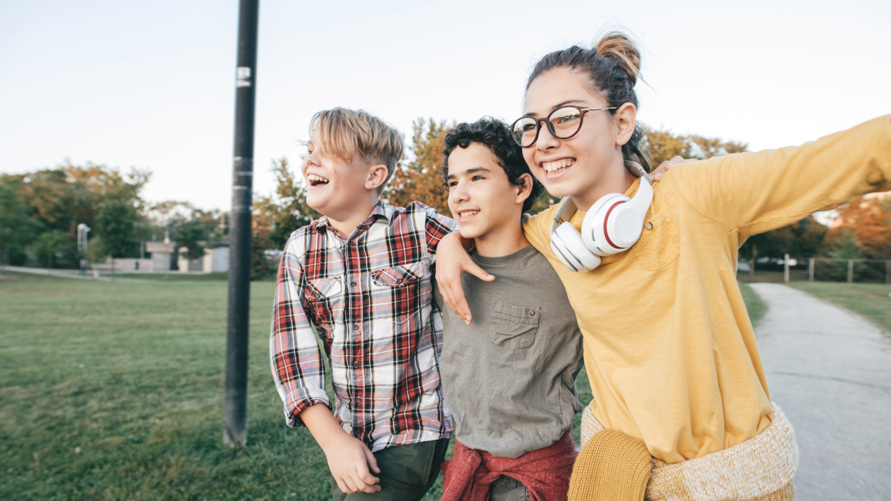 three kids linking arms and happily walking outside