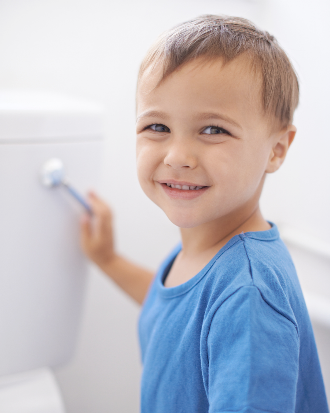 Young boy smiling and happily flushing the potty.