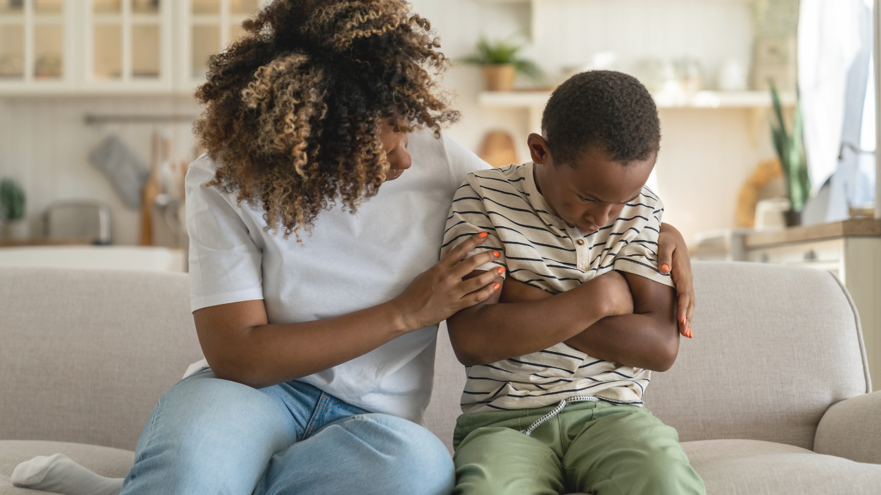 Mom trying to console upset child on the couch