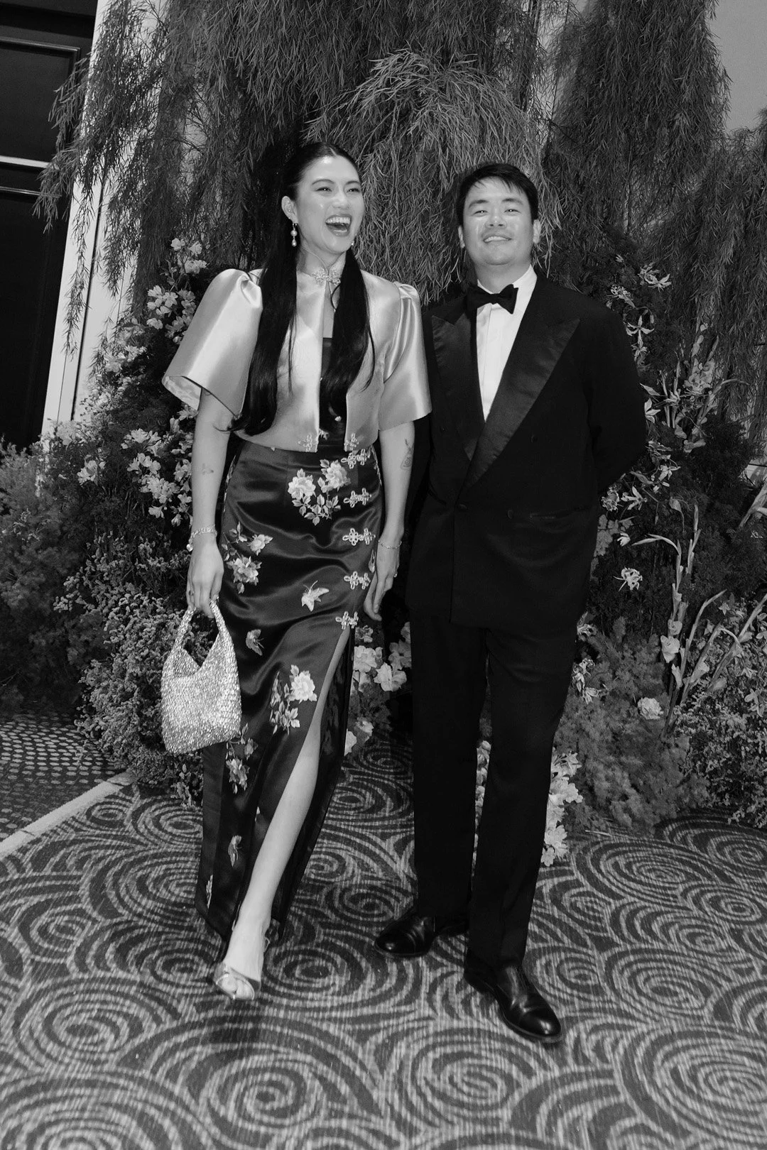 A woman and a man dressed in formal attire posing together at an event.