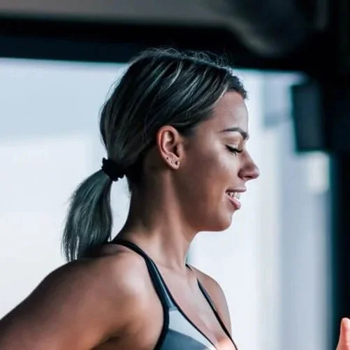 A woman smiling on a treadmill in a gym