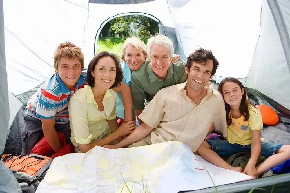Multigenerational family smiling together inside a camping tent with a map