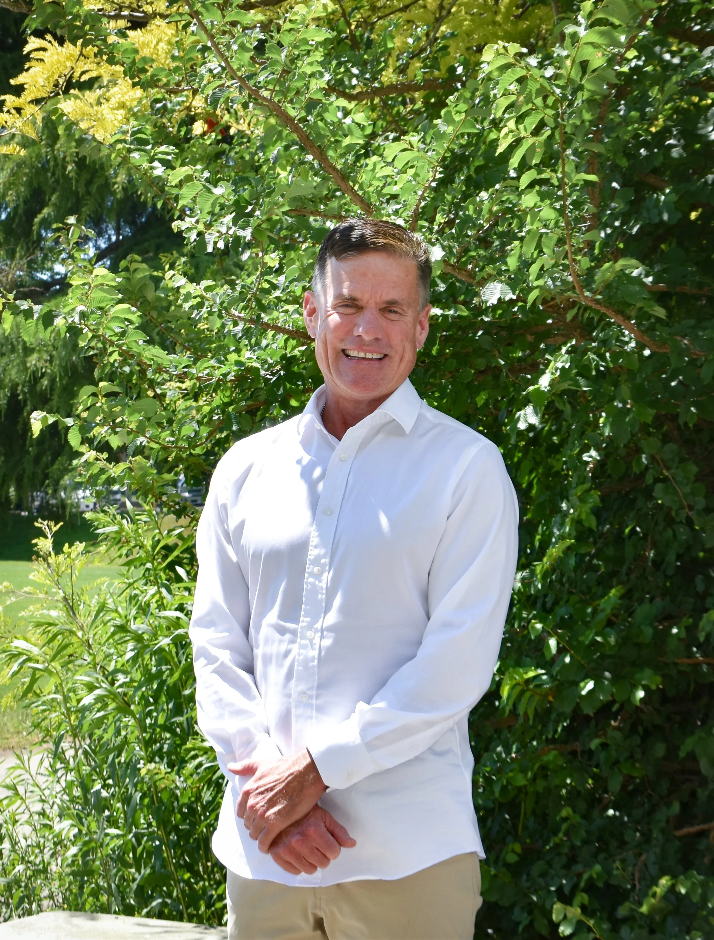 Michael Lattimer, life coach, in white shirt standing in front of lush green foliage