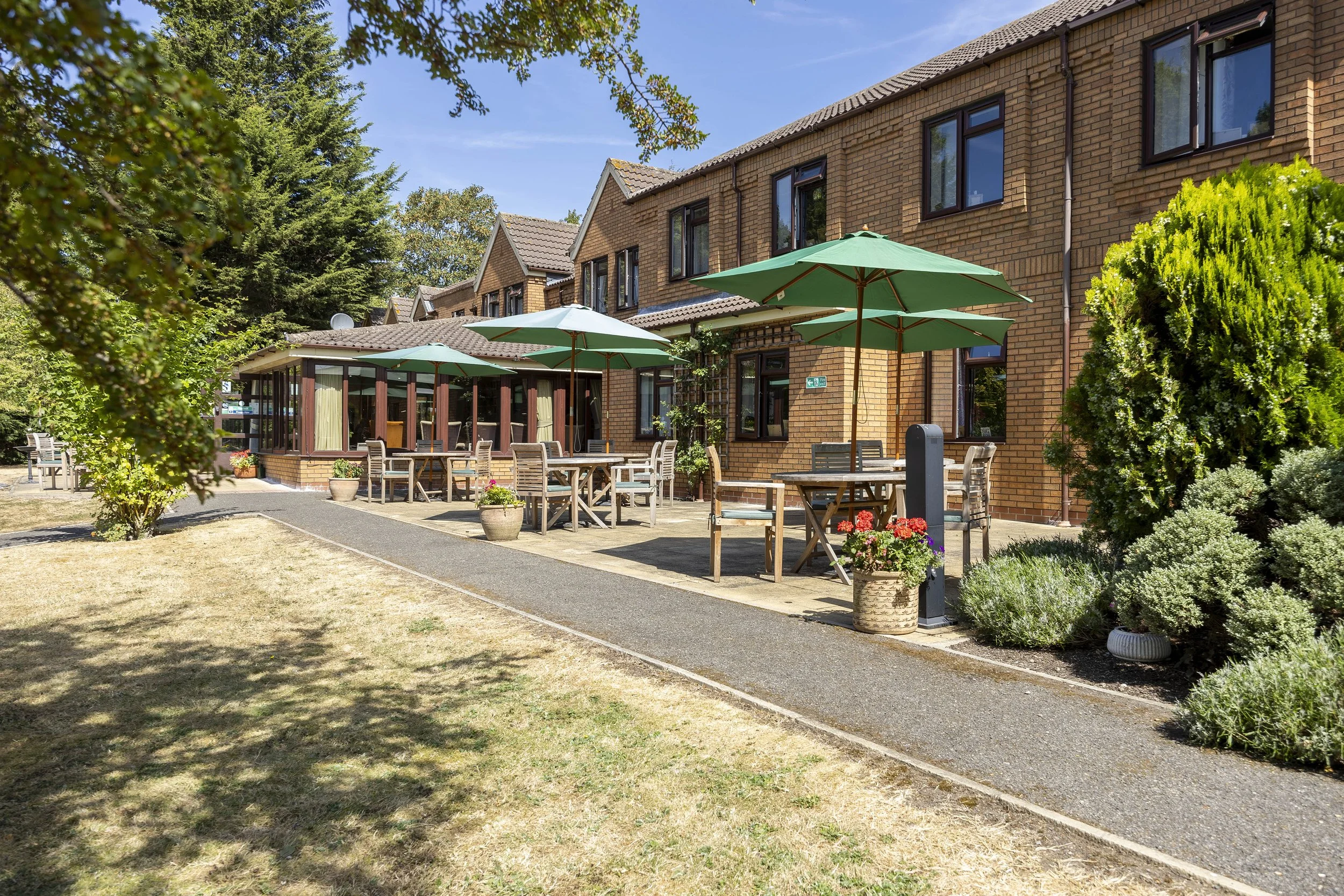 Back garden with tables and green umbrellas 