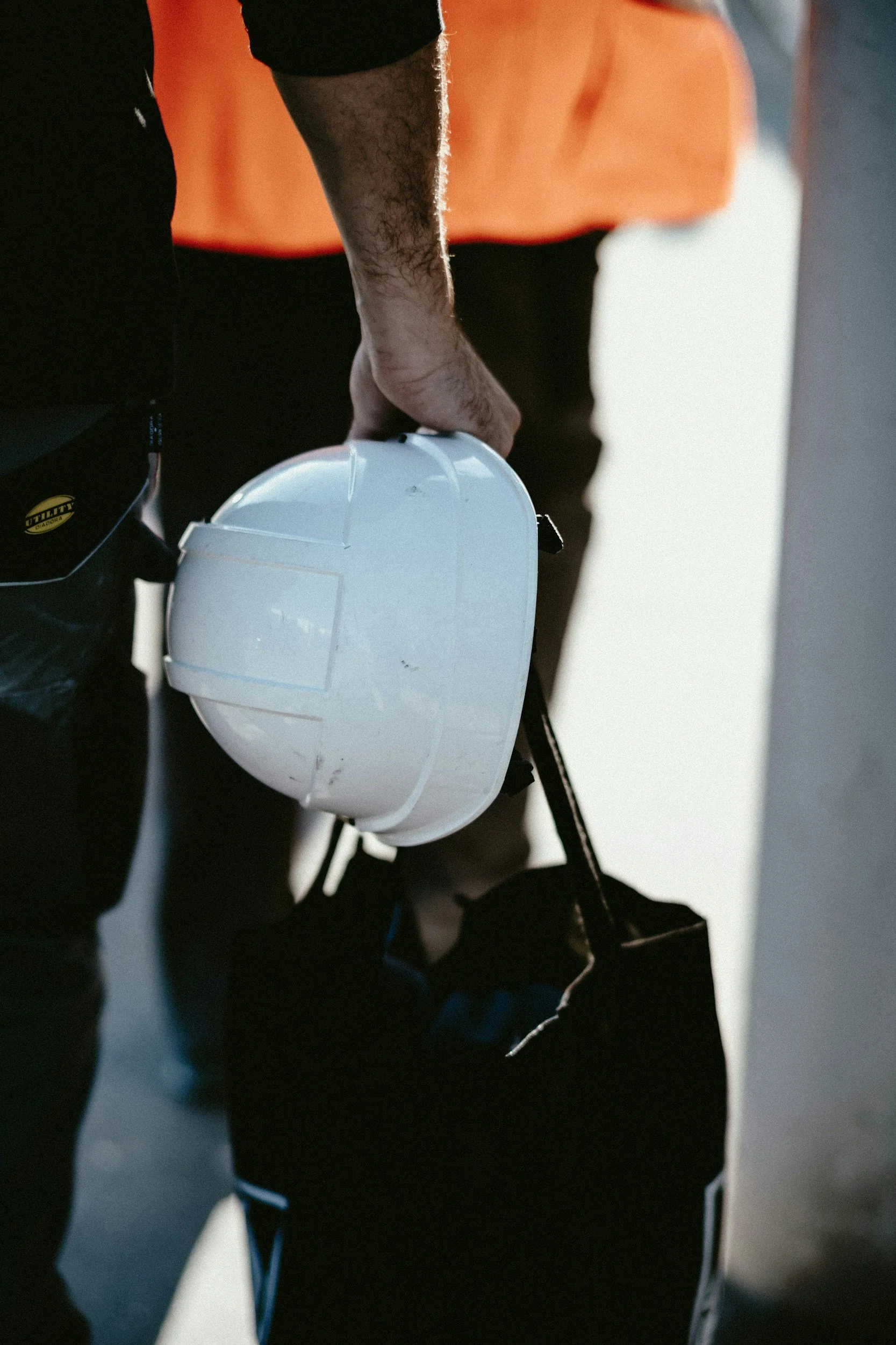 A senior environmental scientist wearing an orange shirt holding a white hard hat in their right hand.