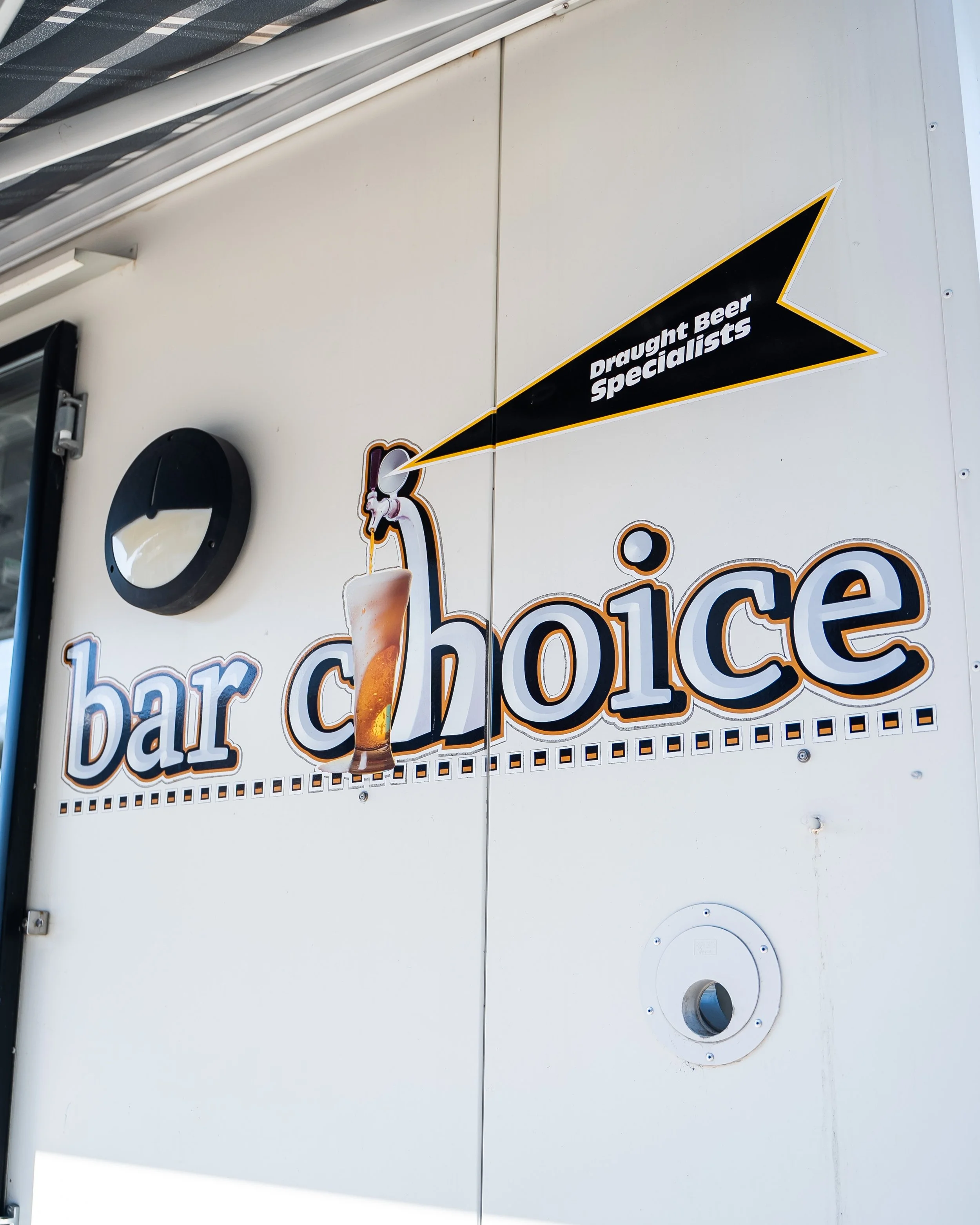 Sign on a wall reading "bar choice" with an image of a beer glass and a small sign saying "Draught Beer Specialists."