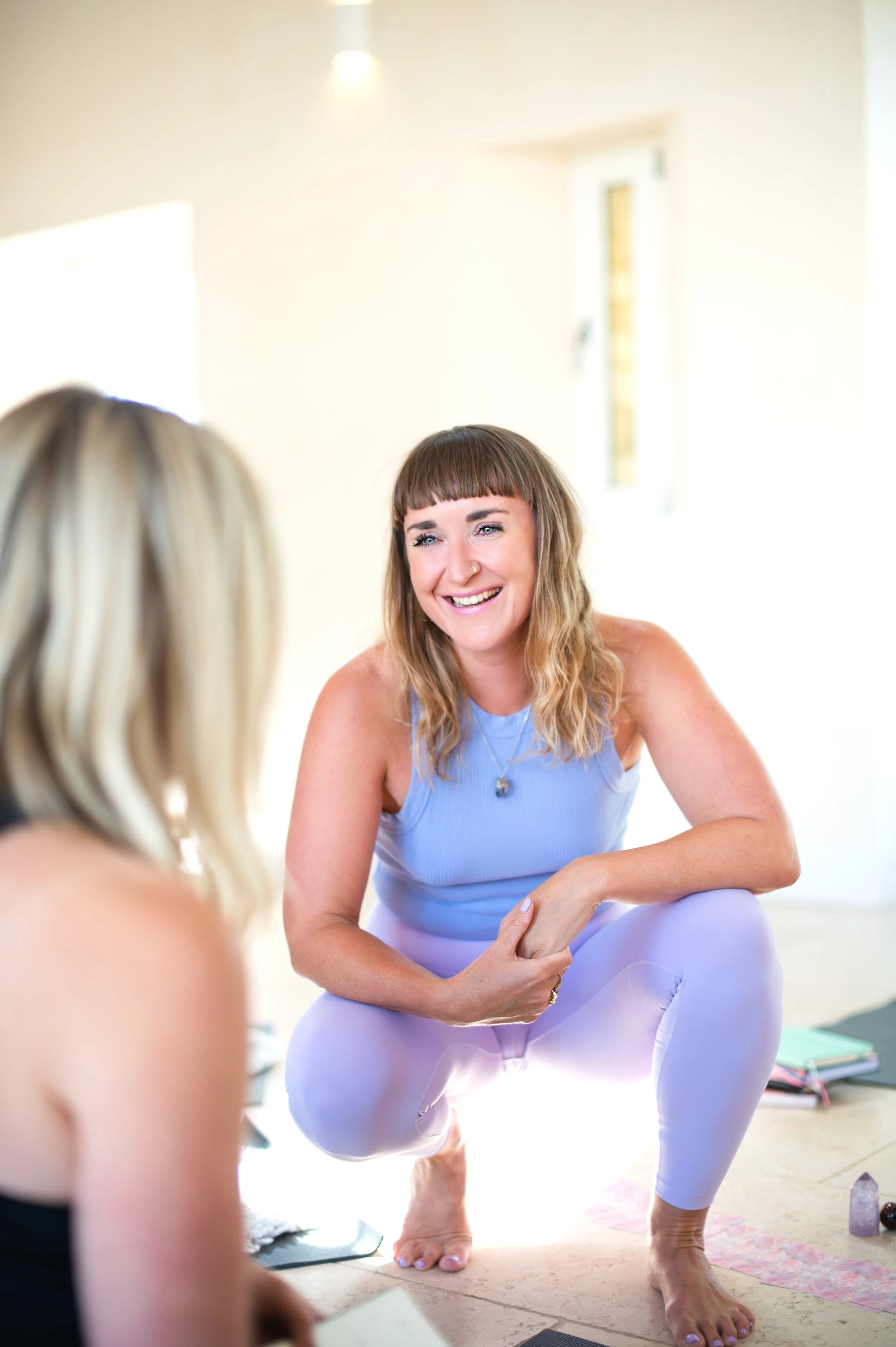 A female yoga psychologist crouching near to a blond woman. Shot by wellness brand photographer Emily Dyer Creative, Oxford UK