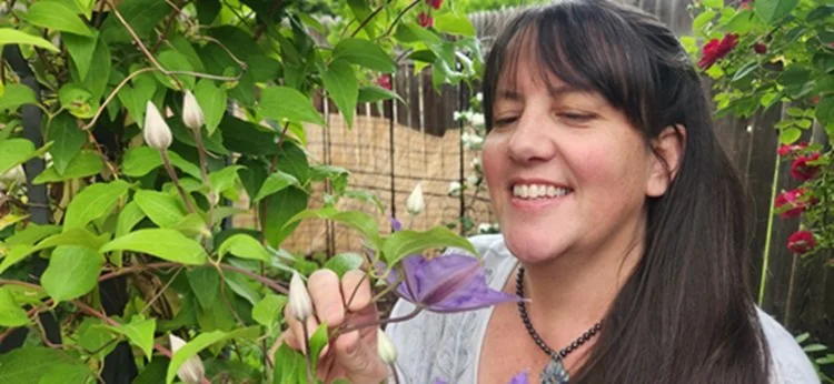 Person smiling and looking at a flower