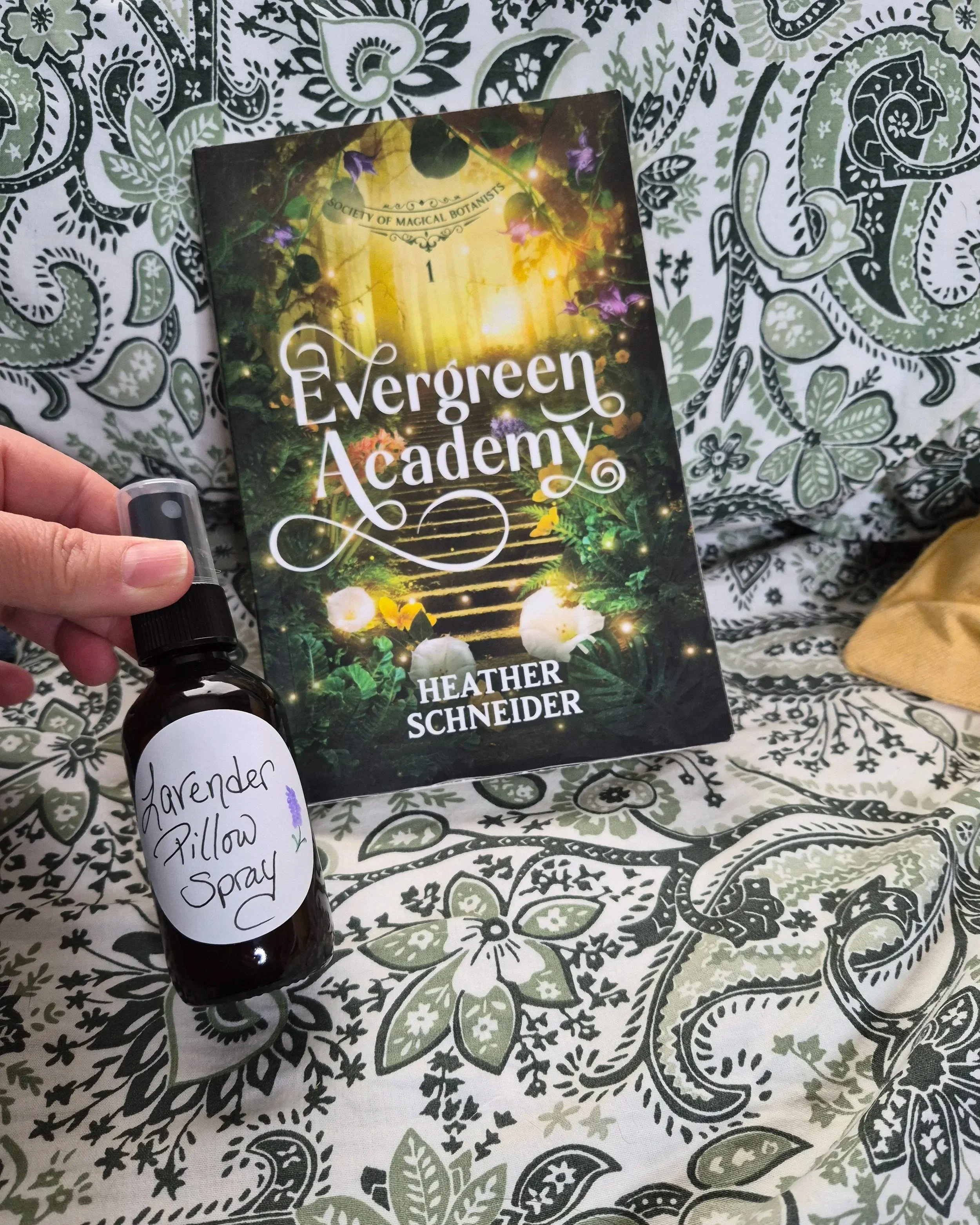 Lavender Pillow Spray bottle next the book Evergreen Academy by Heather Schneider on a bed