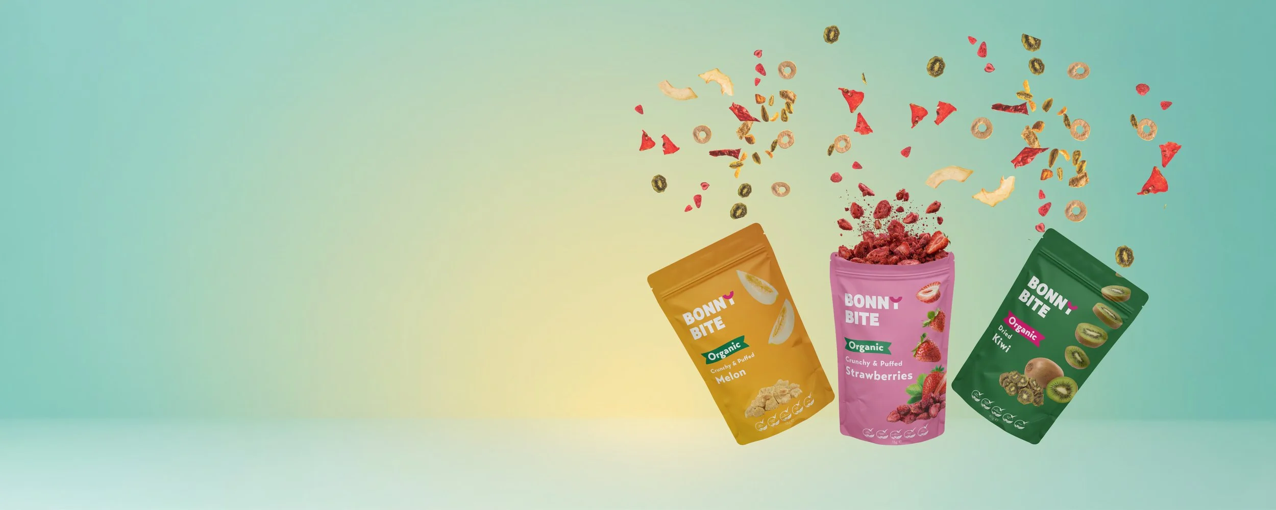 Three snack packs from Bonny Bite, Dried Melon, Crunchy & Puffed Strawberries and Dried Kiwi, with colourful pieces of fruit spilling from the packages, against a pastel green background.
