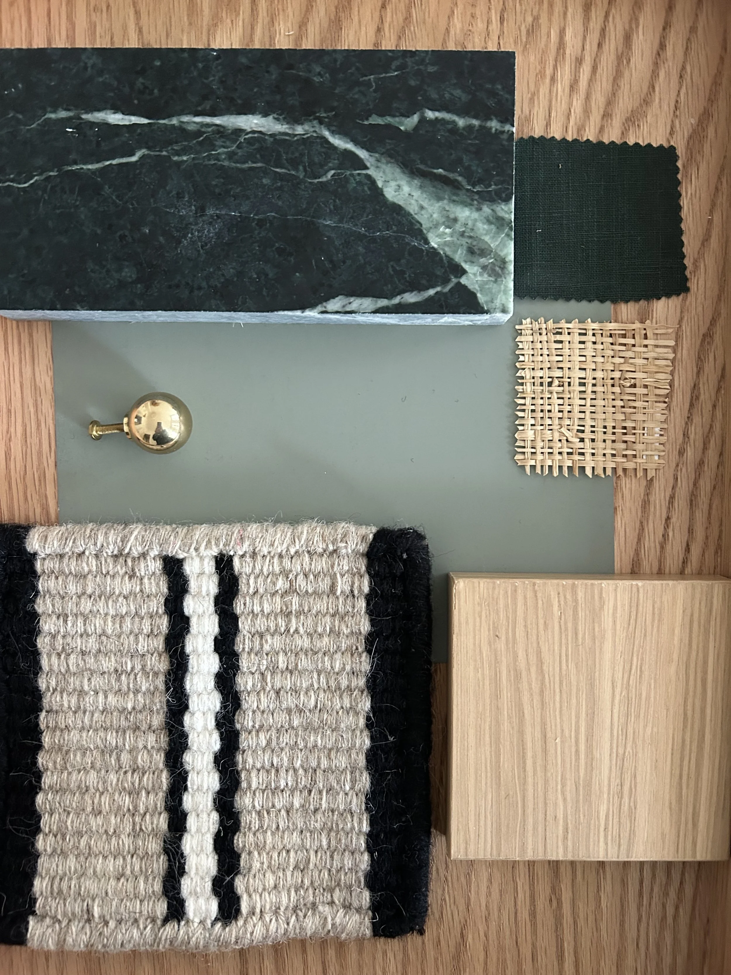 Material board with green marble, light wood, green fabric, rattan and a beige and black carpet