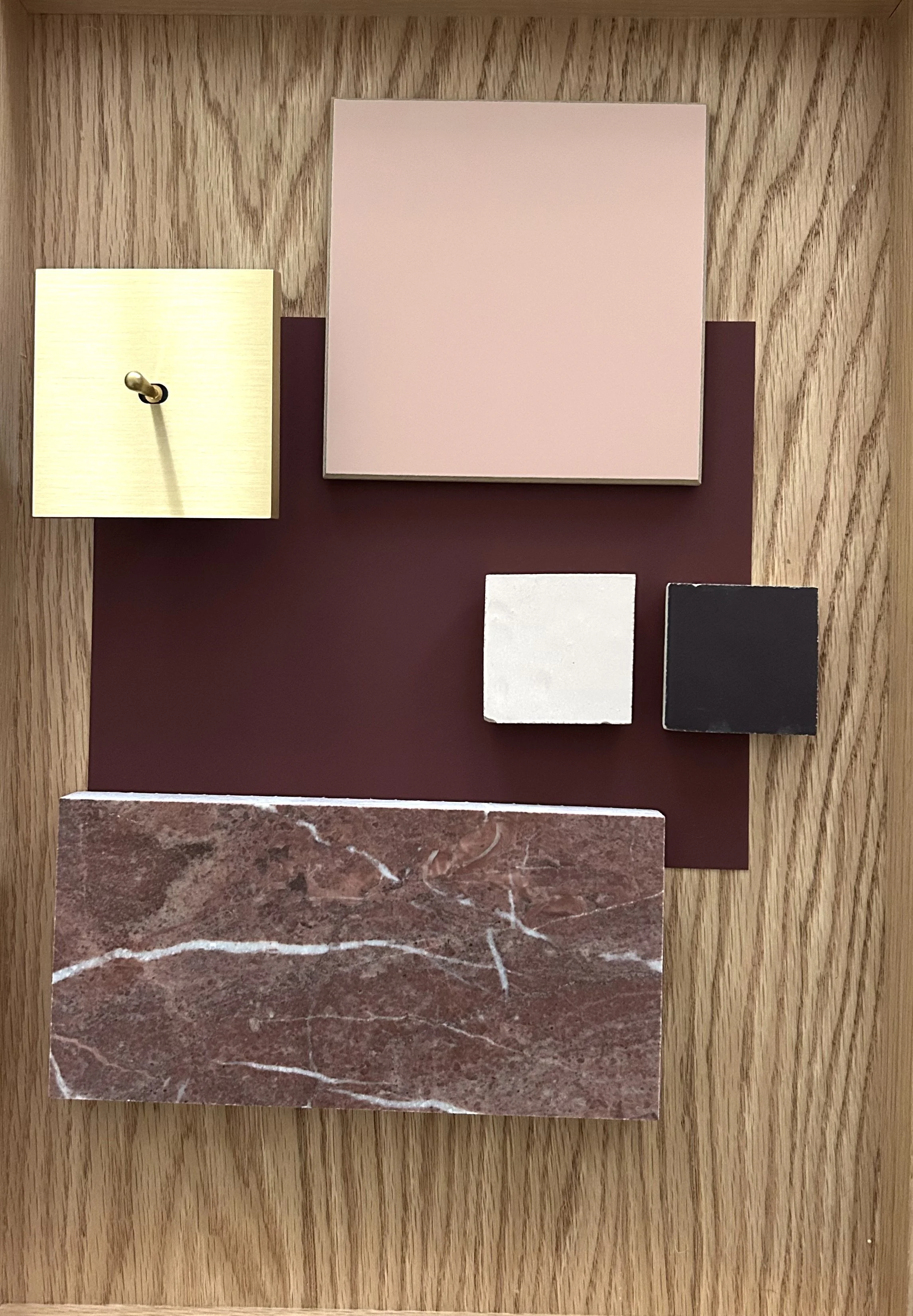 Material board with burgundy and rosa tiles, red marble and a golden light switch