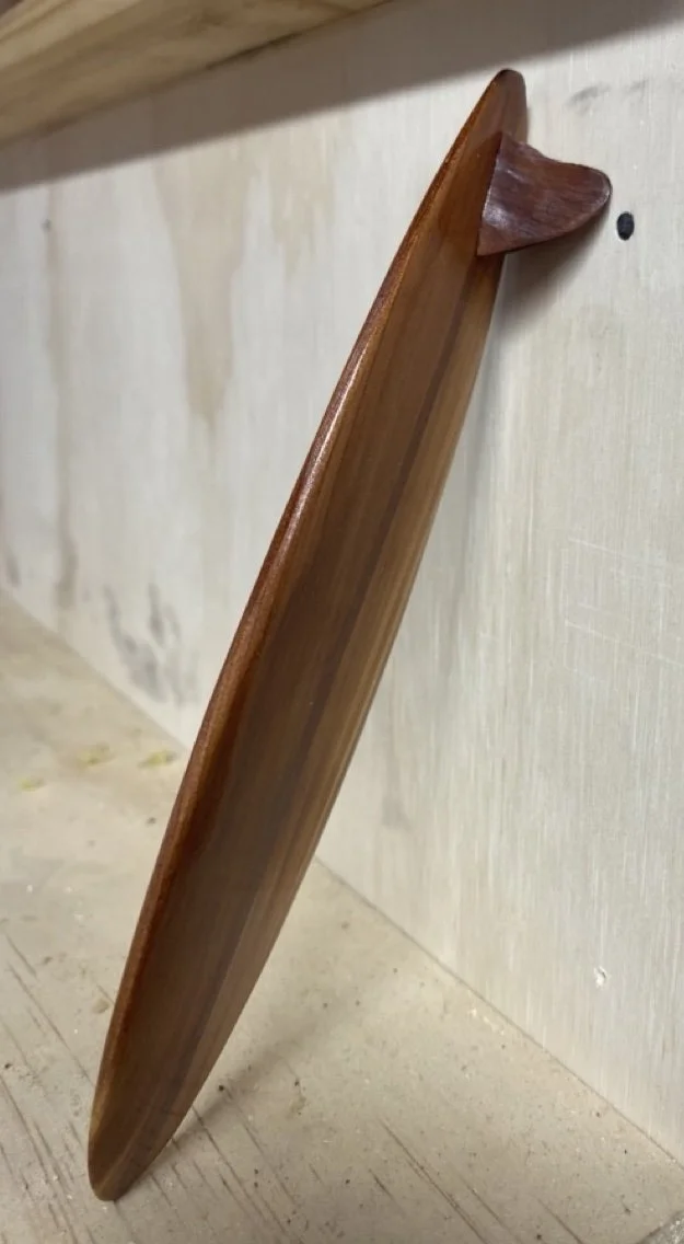 A wooden shelf with a curved end mounted on a wall.