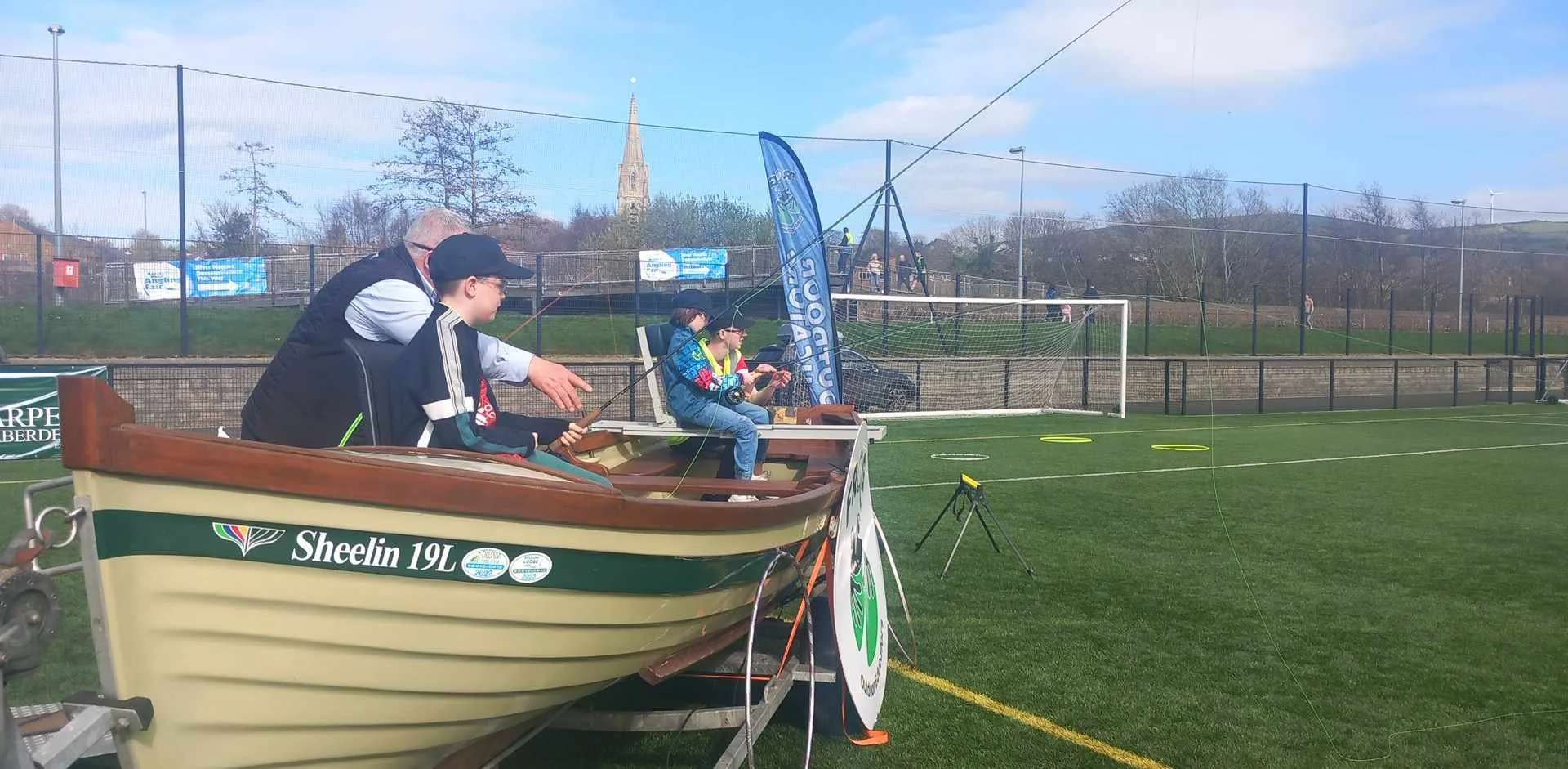 People sitting in a boat by a football field, fishing.