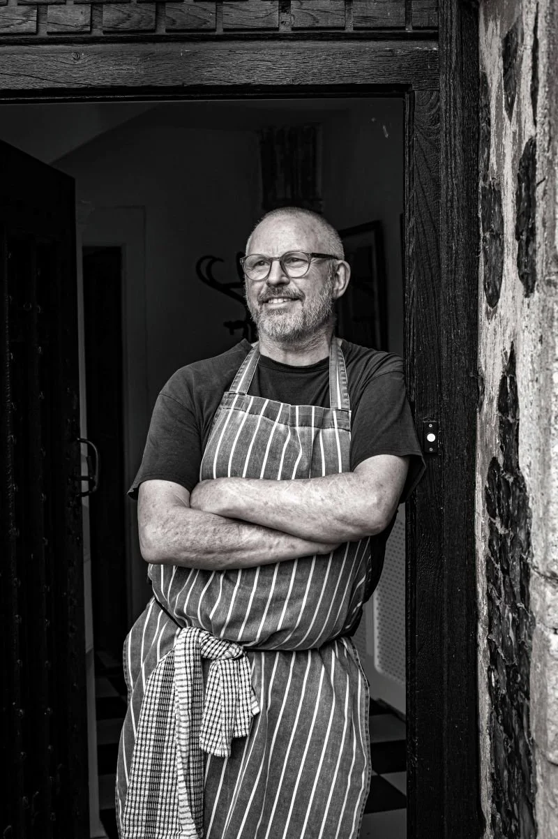 chef peter harrison leaning on the wall at butley priory smiling off camera