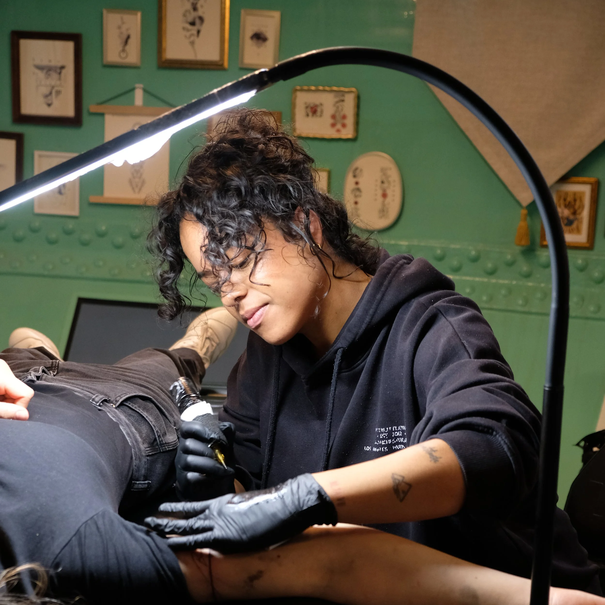 Tattoo-artist die een tattoo maakt op de arm van een klant in een tattoo-studio.