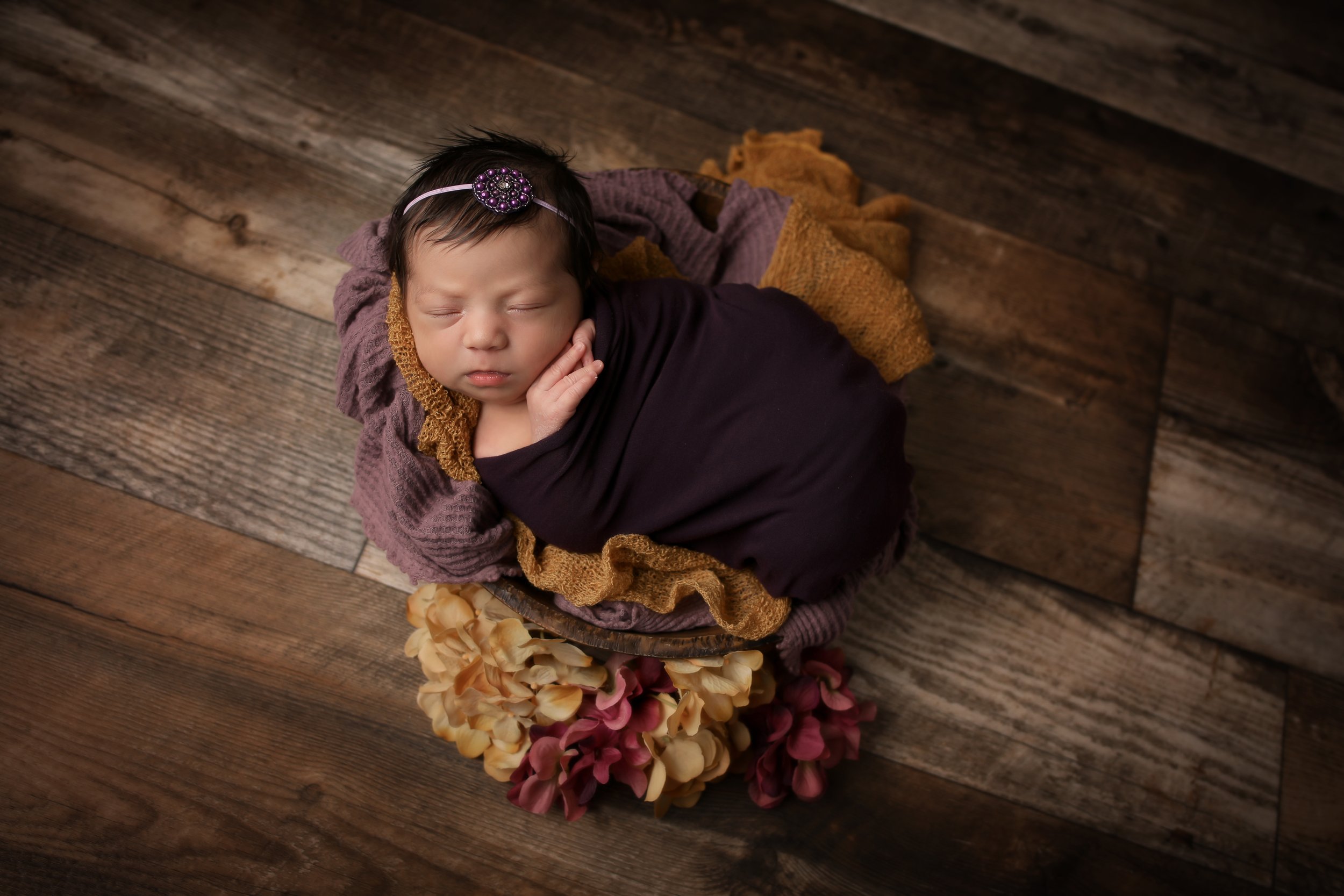purple and yellow flowers with baby in bowl