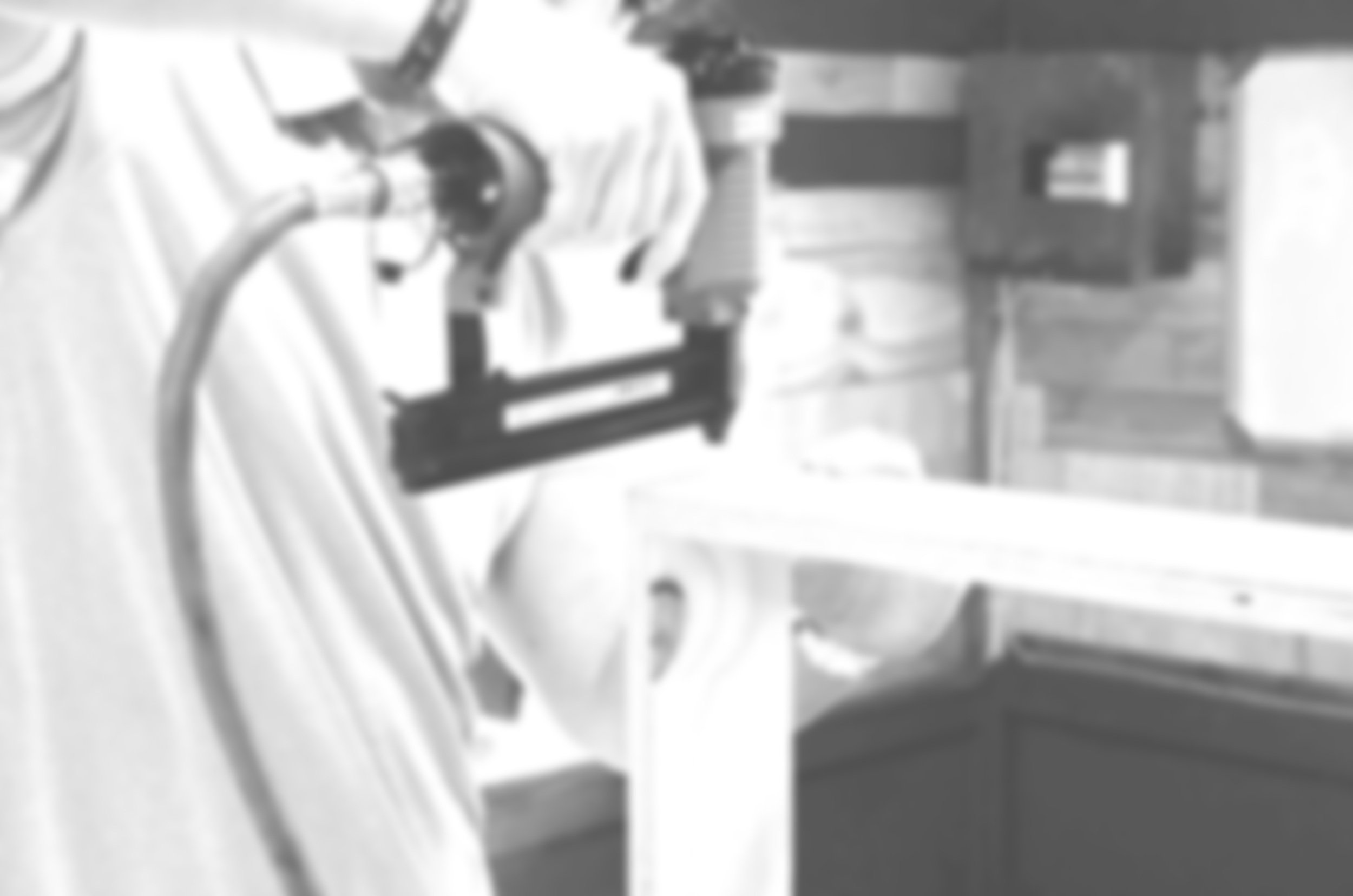 Close-up of a microscope on a white laboratory table with a wooden wall background.