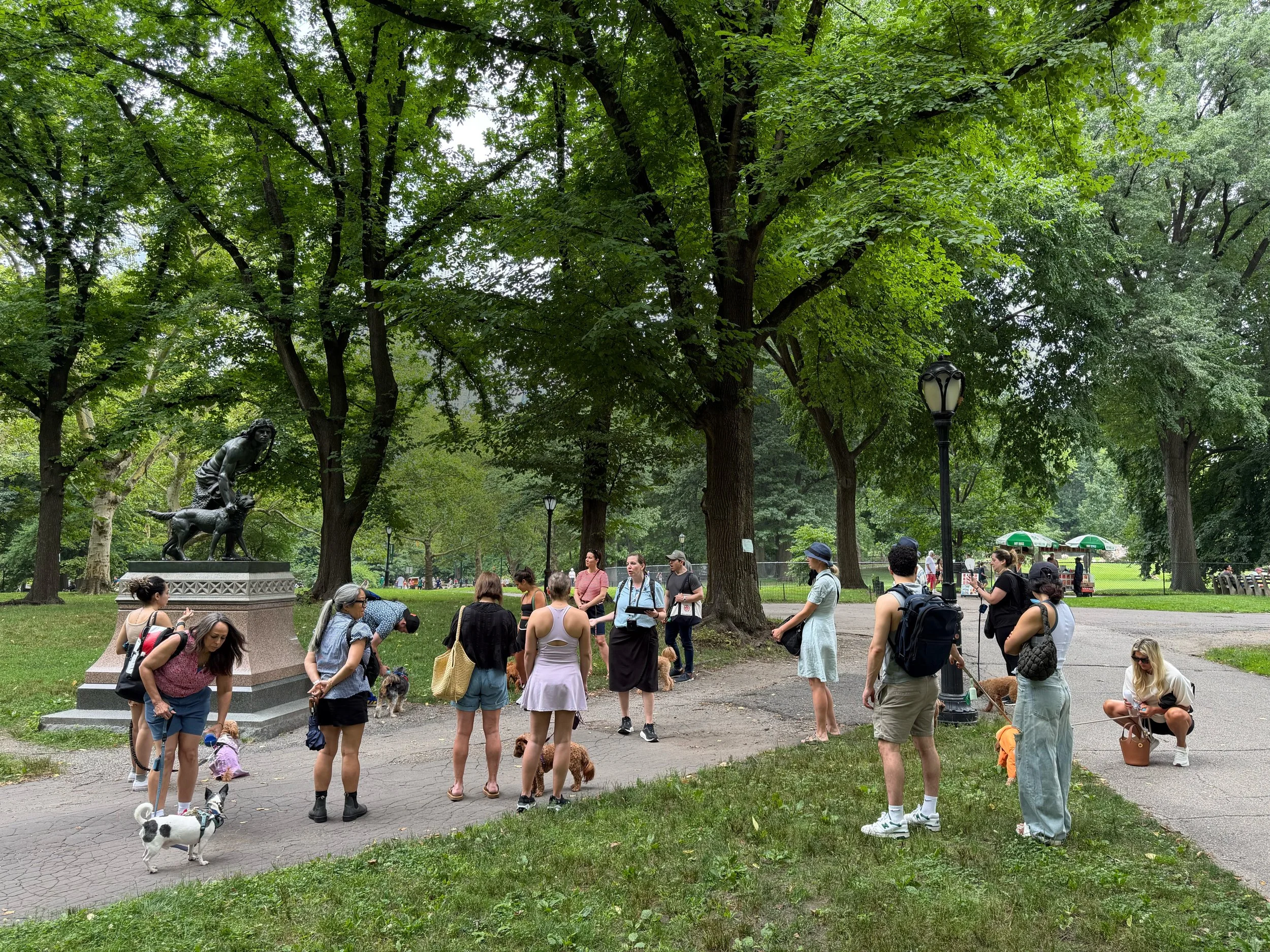 Tour guide talking to group next to the Indian Hunter sculpture in Central Park. 