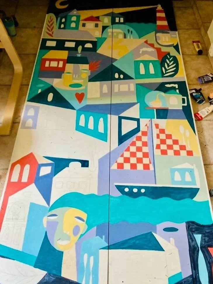 Peinture mural abstraite avec des formes géométriques, maisons colorées, bateau, visage stylisé, et éléments naturels comme un arbre et une mer.