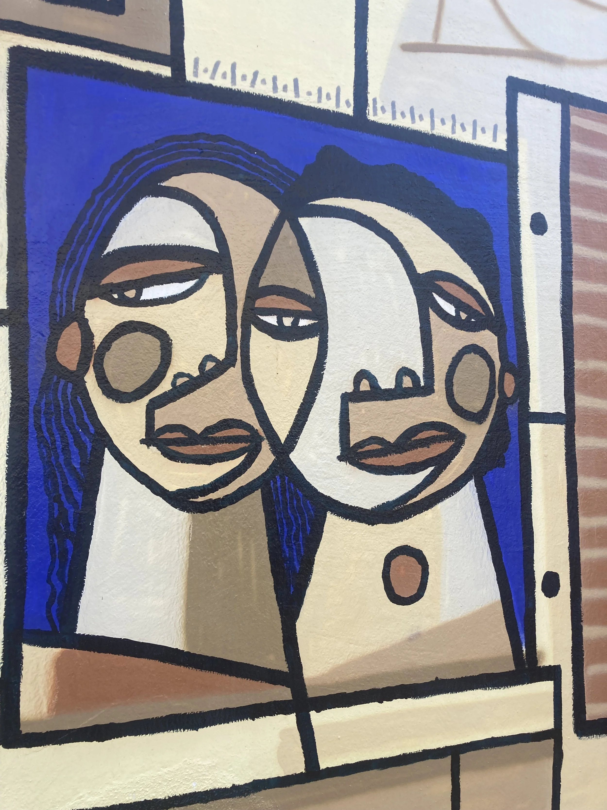 Une peinture abstraite représentant deux visages féminins avec des traits stylisés et des couleurs vives, notamment du beige, du blanc, du noir et du bleu, dans un style cubiste.