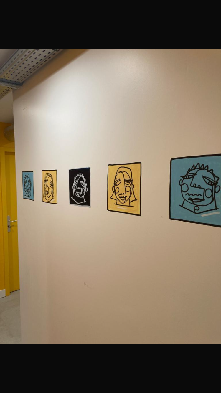 Une série de cinq portraits en style dessin abstrait sur un mur blanc, chacun sur un fond coloré différent (bleu, jaune, noir, beige, bleu).