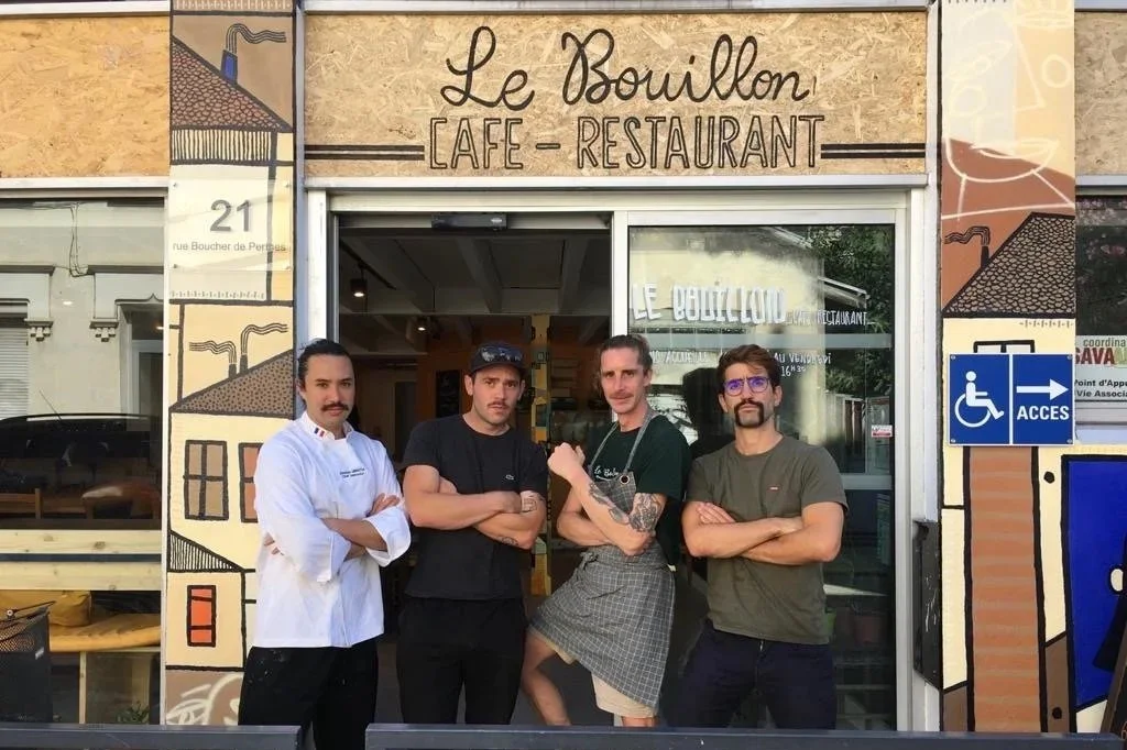 Quatre hommes debout devant l'entrée d'un café-restaurant appelé Le Bouillon.